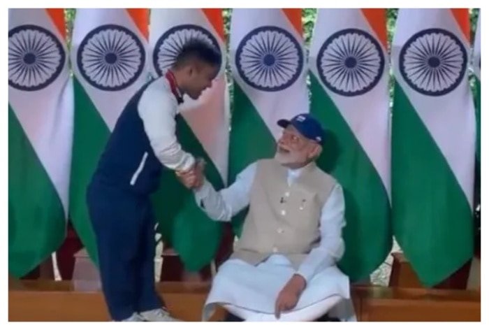 PM Narendra Modi sits on the floor to receive cap from Paralympic javelin star Navdeep Singh